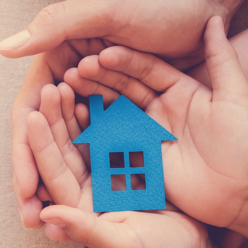 Adult and child hands holding paper house, family home and real estate concept
